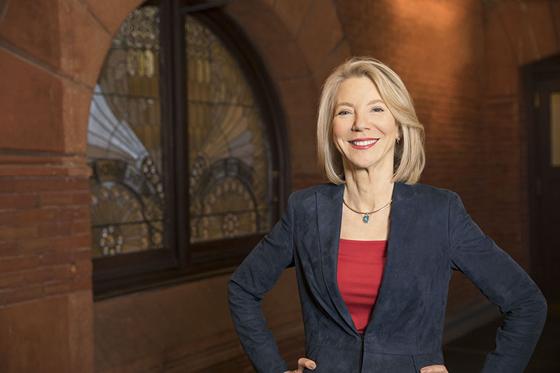 President Gutmann poses before a stained glass panel in. the historic Fisher Fine Arts Library
